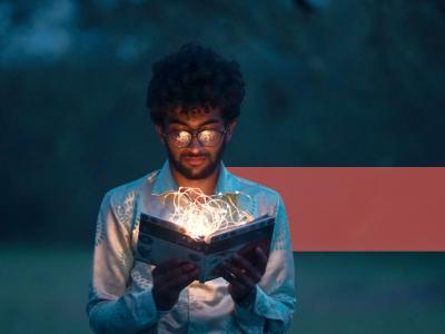 En ung mand læser i en lysende bog